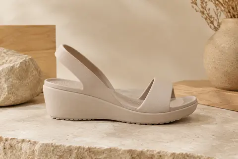 Sandale Crocs Brooklyn Low Wedge au profil compensé bas, présentée sur un fond ivoire et sable.