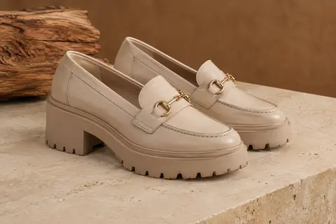 Paire de mocassins femme en simili cuir à détail mors et semelle épaisse crantée, posée sur une pierre claire.