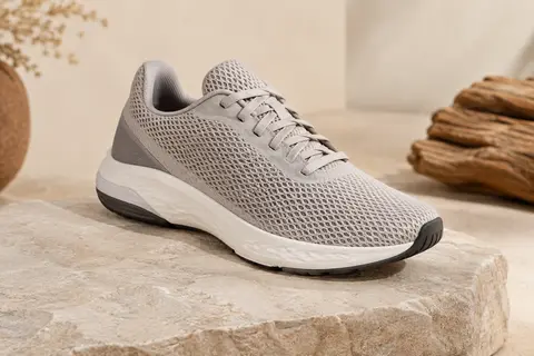 Chaussure de running mixte en mesh avec semelle légère, présentée sur un fond ivoire et sable