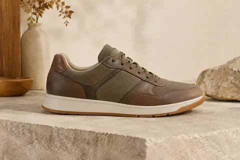 Chaussure basse Skechers pour homme en cuir et textile, présentée sur une pierre mate dans un décor naturel