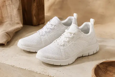 Paire de baskets basses blanches à lacets, avec une tige en maille et des détails superposés.